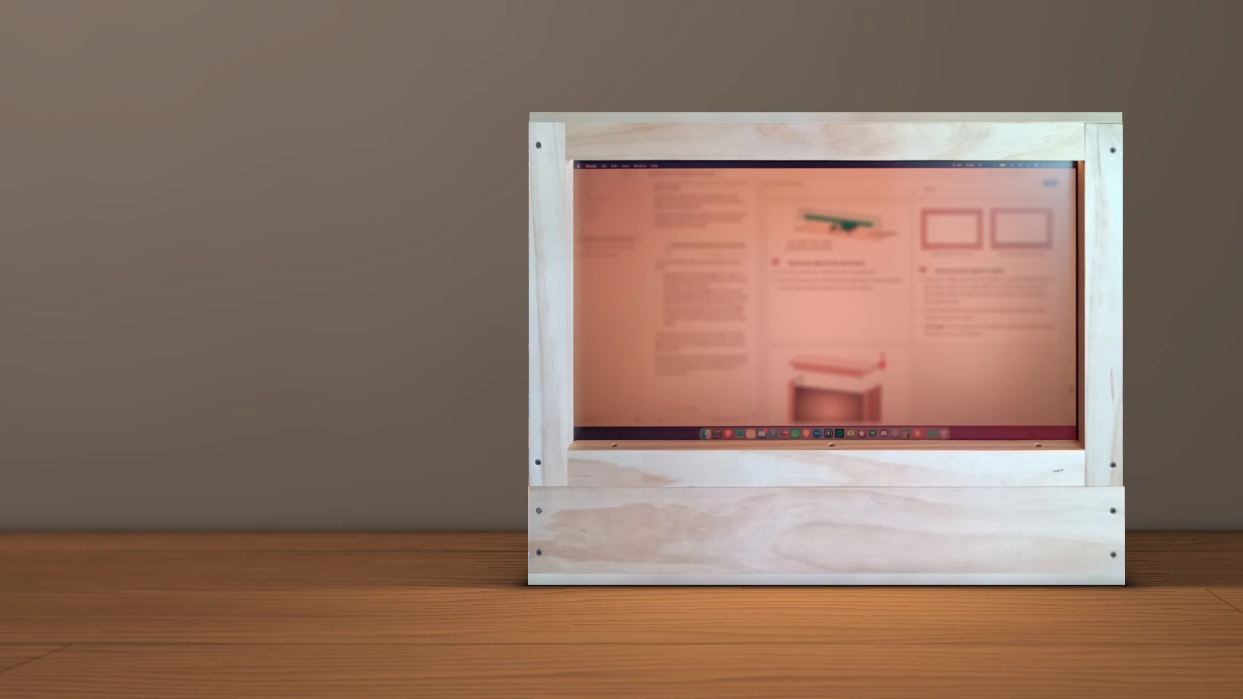 The Firelight straight on: a warm-lit screen in a wooden frame showing a desktop with its menu bar and dock, its glow falling on the desk in front